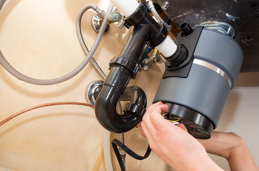 Man installing garbage disposal in home.